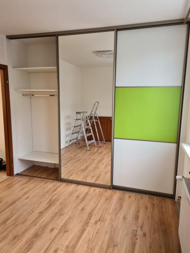 Vestavěná skříň v ložnici s volným prostorem pro TV ve střední části.